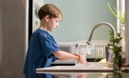 a young boy washing dishes at home